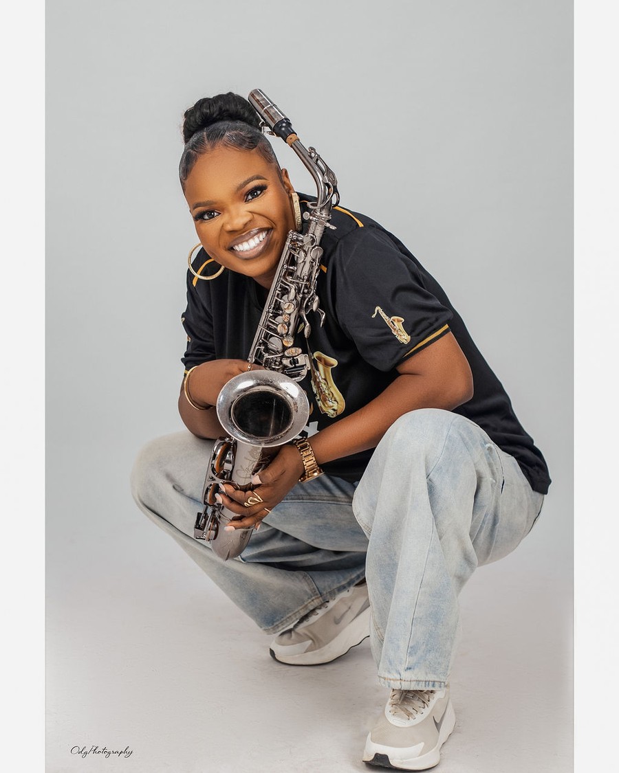 Funmisax crouching with her saxophone in a FunmiSax jersey