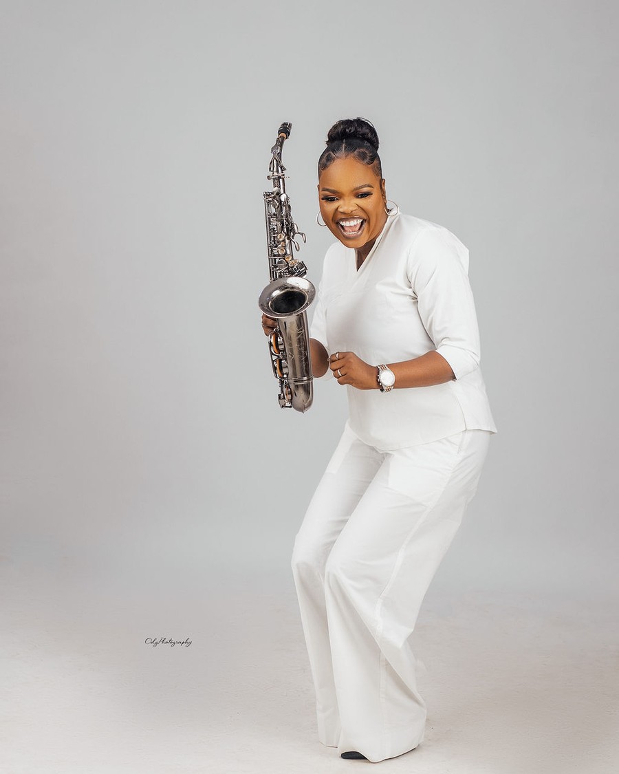Funmisax playing the saxophone in a white suit