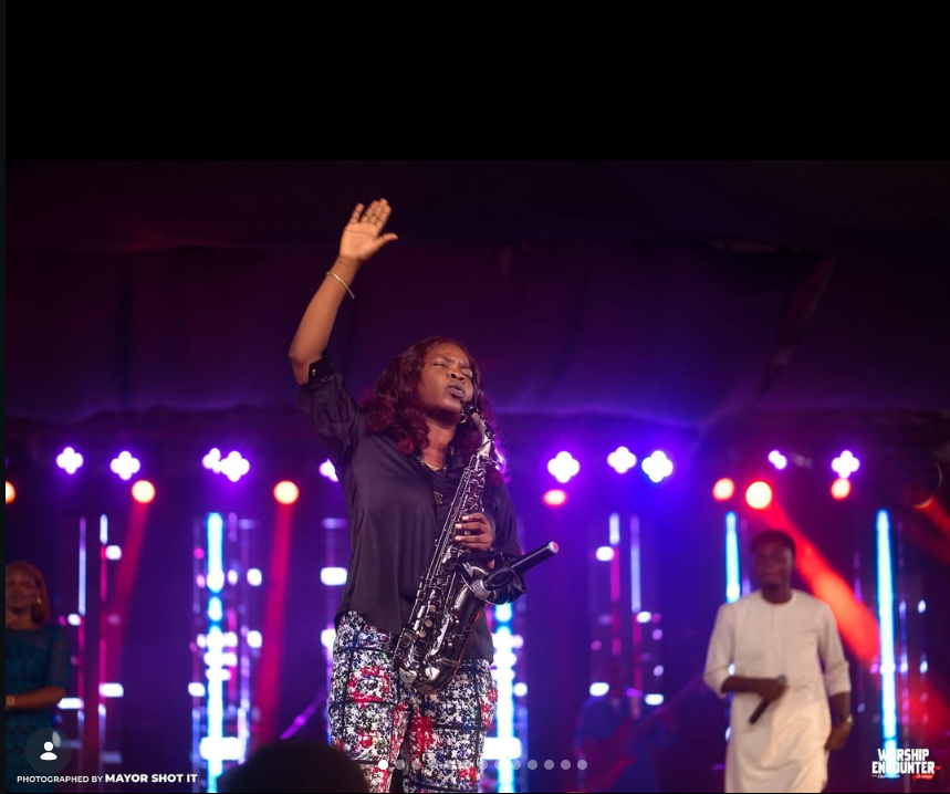 Funmisax with hand raised in worship at Worship Encounter